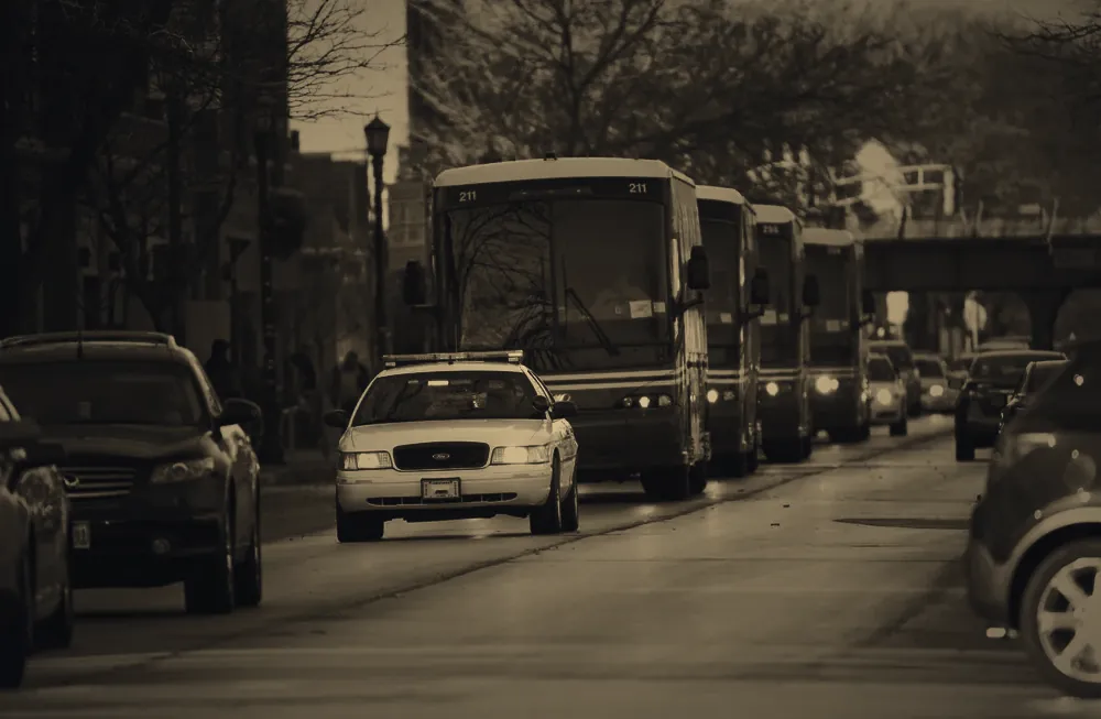 Police escort vehicle ahead of a black chauffeured SUV
